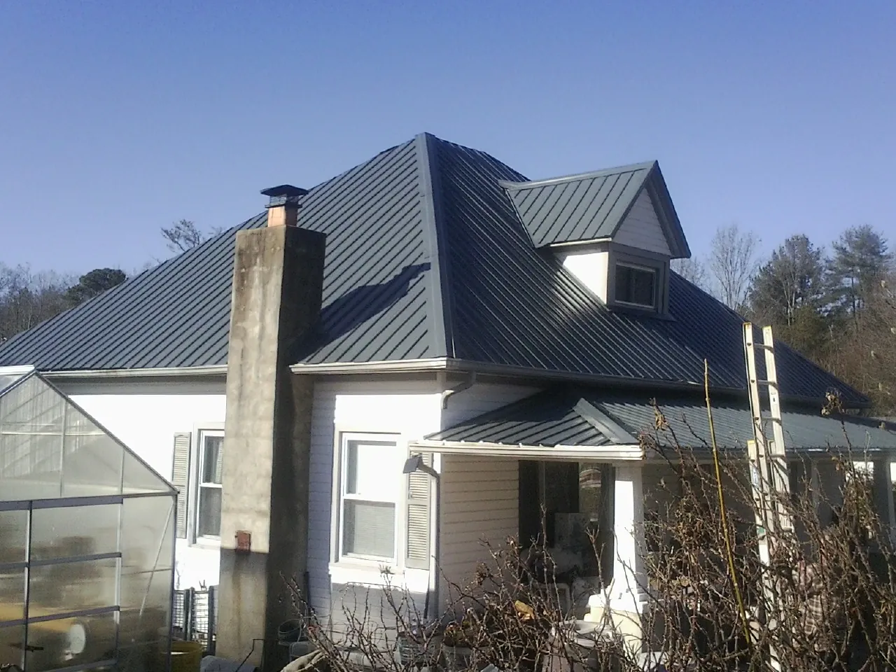 Dark blue standing seam metal roof on a white farmhouse with dormer — Slate & Tile Roof Repair by Roofing Brothers in Hughesville