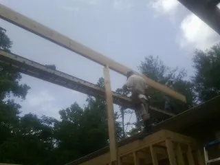 Carpenter setting a ridge beam over a new addition frame — Ice Dam Removal by Roofing Brothers in Hughesville