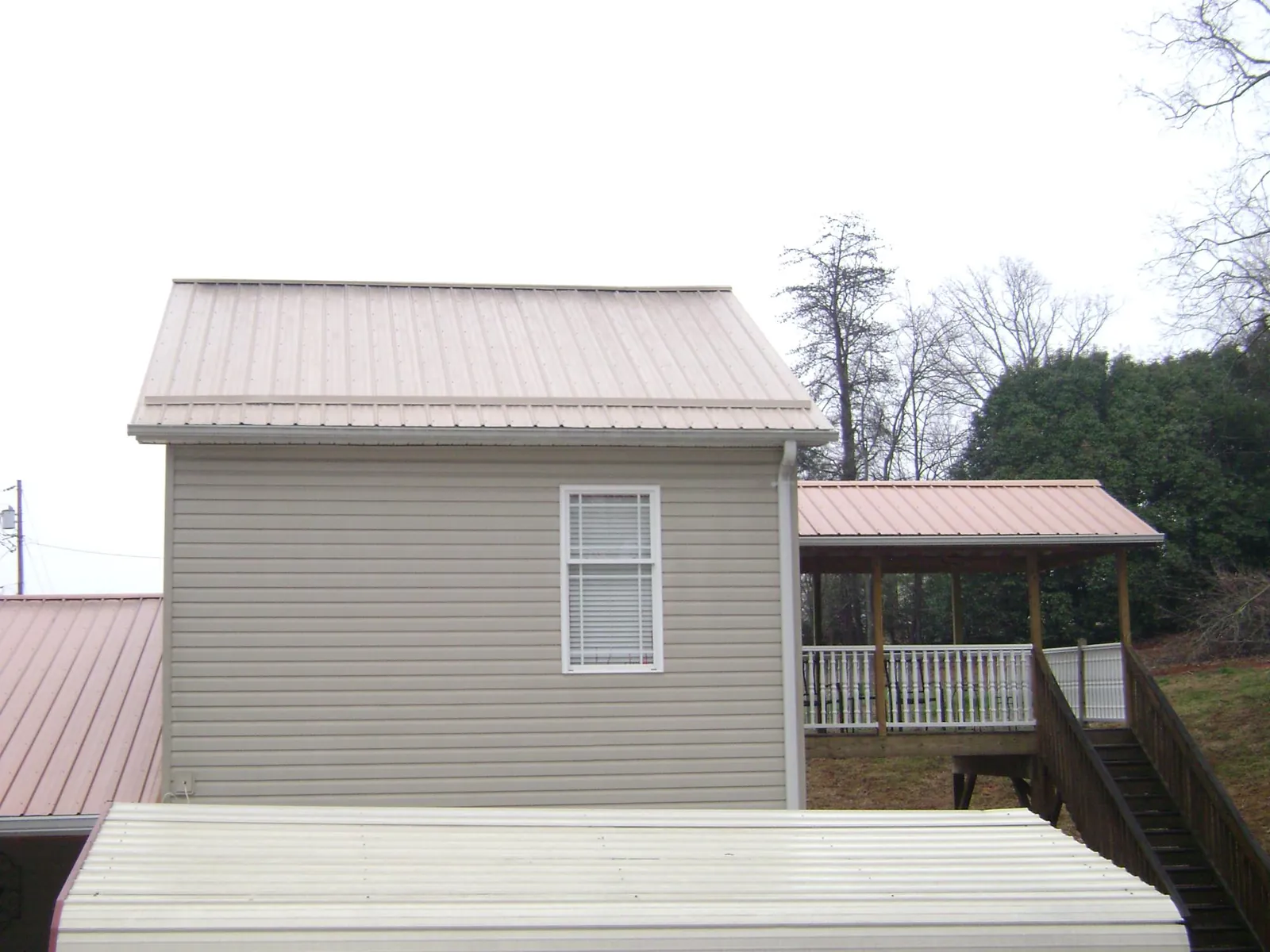 Tan metal roofs on a two story addition and attached porch, from a Roof Replacement job in Hughesville